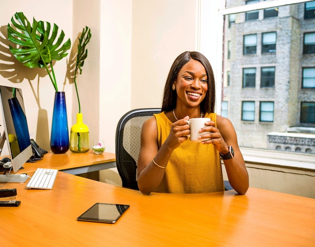 property manager in orange shirt sitting at their desk drinking coffee